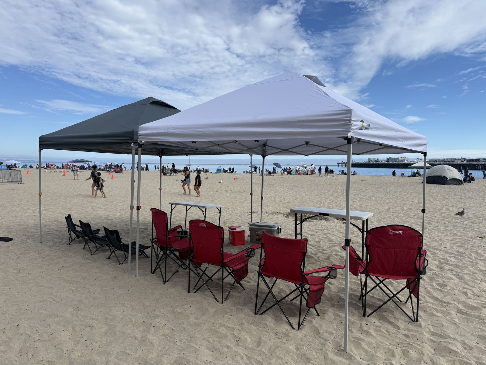 Double canopy setup with chairs, table, and cooler on the sand